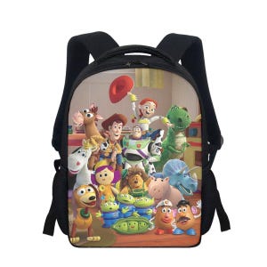 Op de afbeelding: Zwarte rugzak met een kleurrijke print van Toy Story-personages. De rugzak heeft verstelbare schouderbanden, een handvat aan de bovenkant en een hoofdvak met ritssluiting. Het ontwerp toont Woody, Buzz Lightyear en andere personages.