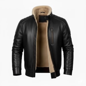 Peut inclure: Une veste en cuir noir avec une doublure en fausse fourrure beige, un col montant à bouton-pression, une poche poitrine verticale zippée, ainsi que des poignets et un ourlet côtelés. La veste présente des détails matelassés aux épaules.