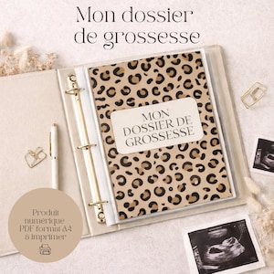 May include: Beige binder with gold details, displaying a leopard print cover with the text "MON DOSSIER DE GROSSESSE". A white pen, gold paper clip, and ultrasound scans are visible. The text "Produit numérique PDF format A4 à imprimer" is also present.