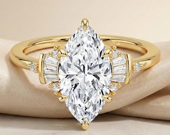 May include: A gold ring featuring a large, marquise-cut diamond as the centerpiece. The ring is accented with smaller, baguette-cut diamonds and round diamonds on the band. The ring is set on a neutral background.