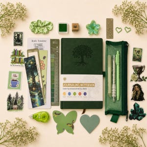 Peut inclure: Ensemble de papeterie verte comprenant un journal avec un motif d'arbre, des stylos, des autocollants et un chouchou. Le journal est intitulé "Journaling Notebook". Éléments décoratifs : papillon et cœur.