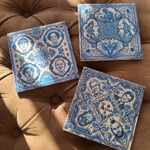 May include: Three square ceramic tiles with blue and white designs. One tile features portraits of The Three Stooges, another has a Godzilla theme, and the third depicts The A-Team characters. Each tile has a decorative border.