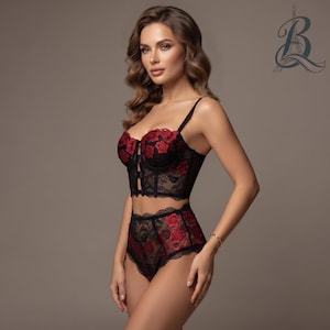 Peut inclure: Un ensemble de lingerie en dentelle noire composé d'un bustier et d'une culotte taille haute. Les deux pièces sont ornées de motifs de roses rouges brodées. Le bustier présente de fines bretelles et un corsage structuré avec des découpes.