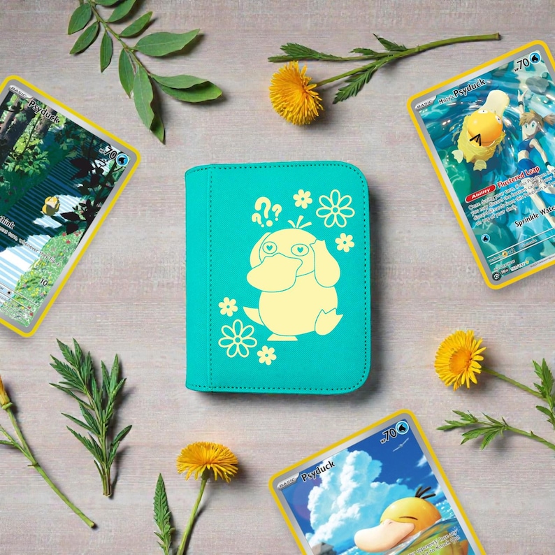 Pu&ograve; includere: Un raccoglitore per carte color verde acqua con una grafica giallo chiaro del personaggio Psyduck circondato da piccole icone di fiori e punti interrogativi, posizionato tra diversi fiori gialli e foglie verdi.