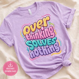 Puede incluir: Una camiseta de color lila claro con la frase "Overthinking Solves Nothing" en una fuente colorida y de burbujas. La camiseta tiene las mangas enrolladas y un nudo en la parte inferior. Un círculo rosa con "Descarga instantánea" está en la esquina inferior izquierda.