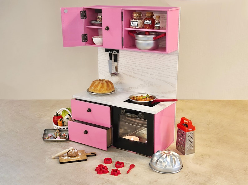 K&ouml;nnte beinhalten: Eine rosa Spielzeugk&uuml;che mit Herd, Backofen und Schr&auml;nken. Zubeh&ouml;r umfasst einen Kuchen, eine Pfanne mit Essen, eine Reibe und Backutensilien. Das Set ist f&uuml;r Kinderspiele und fantasievolles Kochen konzipiert.
