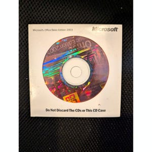 以下が含まれることがあります： 白いケースに入ったMicrosoft Office Basic Edition 2003のCD-ROM。CDはホログラフィックな表面を持っています。ケースにはMicrosoftのロゴと「Do Not Discard The CDs or This CD Case」というテキストがあります。