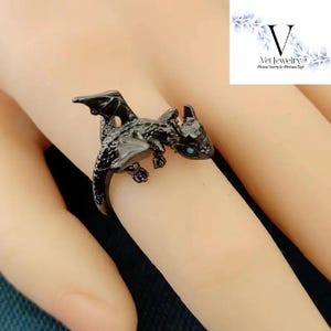 Puede incluir: Anillo de drag&oacute;n negro con ojos turquesa. El drag&oacute;n tiene alas detalladas y un cuerpo texturizado. El anillo se lleva en un dedo. Joyer&iacute;a &uacute;nica.