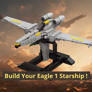 May include: A gray and white plastic brick starship model featuring yellow accents, dual engines, and a black cockpit, mounted on a black display stand. The text "Build Your Eagle 1 Starship !" is displayed in yellow letters on a dark rectangular background.