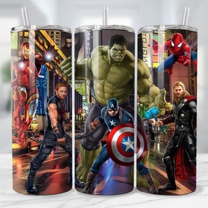 May include: Three stainless steel tumblers with superhero graphics. Each tumbler features a different character: Iron Man, Hawkeye, Hulk, Captain America, Spider-Man, and Thor. The background depicts a city scene with bright lights.