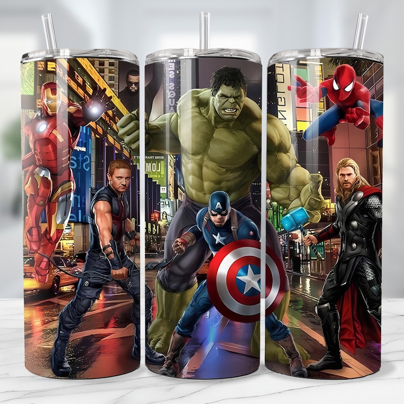 May include: Three stainless steel tumblers with superhero graphics. Each tumbler features a different character: Iron Man, Hawkeye, Hulk, Captain America, Spider-Man, and Thor. The background depicts a city scene with bright lights.