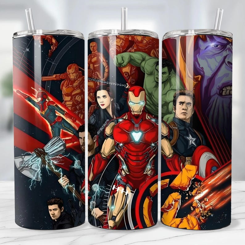 May include: A set of three stainless steel tumblers featuring a vibrant collage of Marvel superheroes. The designs include Iron Man, Captain America, Hulk, and Thanos, with a straw. The tumblers are cylindrical and suitable for cold beverages.