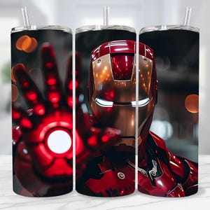 May include: A stainless steel tumbler featuring a vibrant illustration of Iron Man. The design showcases Iron Man's iconic red and gold armor, with a glowing hand and a blurred background. Includes a clear straw and lid.