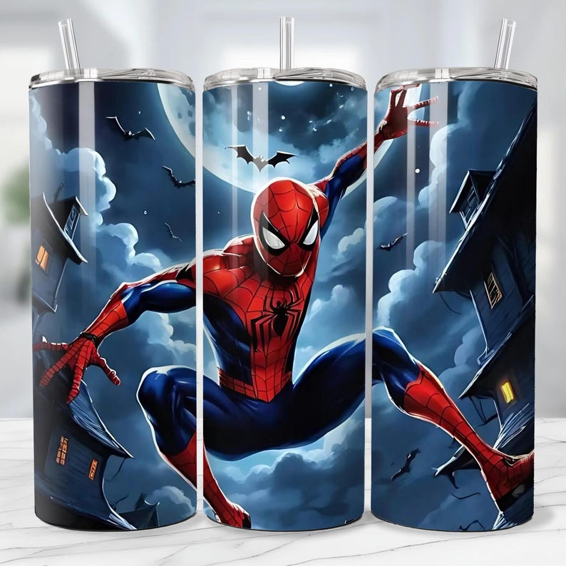 May include: A set of three stainless steel tumblers featuring a Spiderman design. The design shows Spiderman in a dynamic pose against a night sky with a full moon, bats, and spooky houses. Each tumbler has a clear straw.