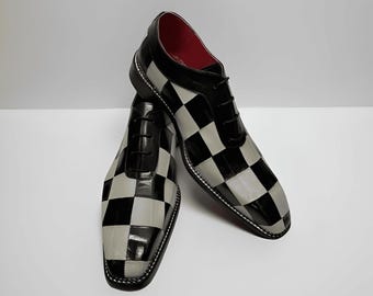 May include: A pair of black and white checkered dress shoes with a glossy finish. The shoes have a classic lace-up design, a black leather upper, and a red interior. The shoes are displayed on a white surface.