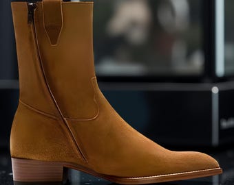 Puede incluir: Botín de tobillo de ante marrón con cremallera lateral y tacón de madera apilado. La bota tiene punta afilada y suela de cuero. La bota es de color neutro y se puede usar con muchos atuendos.