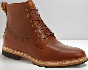 May include: A brown leather boot with a cap toe and lace-up closure. The boot features a stacked sole with a light brown midsole and a dark brown outsole. The upper has decorative stitching and a pull tab at the back.
