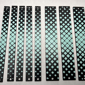 May include: A collection of black rectangular strips with a repeating pattern of aqua-colored squares. Each strip has a hole at the top and the aqua pattern fades from the bottom to the top. The strips are of varying lengths.
