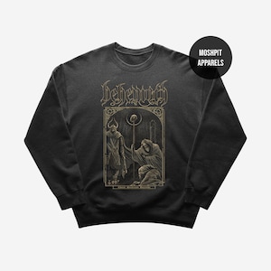 May include: Dark gray sweatshirt featuring a detailed graphic with the word "Behemoth" in gold lettering. The graphic depicts figures in a gothic style. The sweatshirt has a crew neck and long sleeves. The brand logo "Moshpit Apparels" is in a black circle.