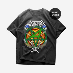 May include: Dark grey Anthrax band t-shirt. The graphic features a green star within a red and yellow circle, with the band's name above. The design includes skulls, hands, and the text "Caught in a Mosh."