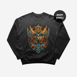 May include: Black crewneck sweatshirt featuring a detailed graphic design. The design includes a stylized dragon head, wings, flames, and the text "IN FLAMES" in orange. The sweatshirt has a round neckline and long sleeves.