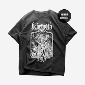 May include: Dark gray t-shirt featuring a detailed black and white illustration of a robed figure with long hair, holding a sword. The word "behemoth" is printed above the illustration in a gothic font. The shirt also has the text "Moshpit Apparels".