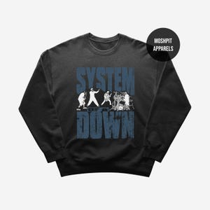 Könnte beinhalten: Dunkelgraues Sweatshirt mit dem Bandnamen "SYSTEM OF A DOWN" in verblichenen blauen Buchstaben. Eine weiße Grafik der Bandmitglieder beim Auftritt ist unter dem Bandnamen zentriert. Der Markenname "MOSHPIT APPARELS" befindet sich in einem schwarzen Kreis.