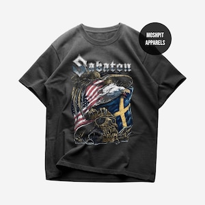 Könnte beinhalten: Dunkelgraues T-Shirt mit einem grafischen Design mit dem Wort "Sabaton" in gotischer Schrift. Das Design umfasst eine amerikanische Flagge, eine schwedische Flagge, einen Adler und einen Totenkopf.