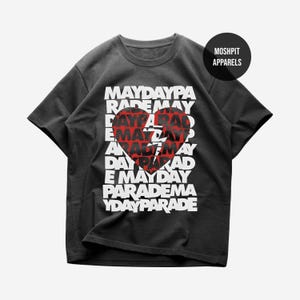 May include: Dark gray t-shirt with the text "MAYDAY PARADE" in white, arranged vertically around a red heart graphic. The shirt has a crew neck and short sleeves. The brand logo "MOSHPIT APPARELS" is on the upper right.