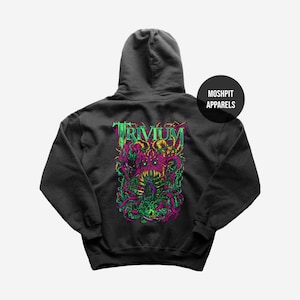 May include: Dark gray hooded sweatshirt featuring a vibrant graphic on the back. The design includes the word "TRIVIUM" in green, with a detailed, colorful illustration of a monster. The brand name "MOSHPIT APPARELS" is printed on a black circle.