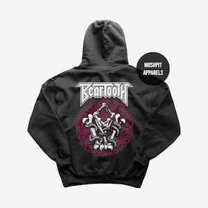 May include: Dark grey hoodie with a graphic design on the back. The design features the band name "BEARTOOTH" in white, above a circular illustration of skeletons, snakes, and roses in white and pink. The hoodie also has a "MOSHPIT APPARELS" logo.