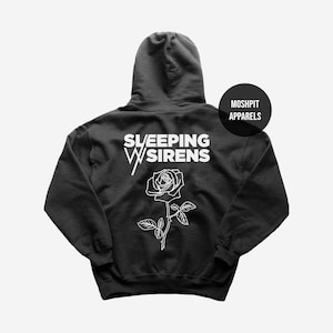 Puede incluir: Sudadera con capucha negra con el texto blanco "SLEEPING WITH SIRENS" sobre un gráfico de rosa blanca. La sudadera tiene una capucha con cordón y un bolsillo tipo canguro. La marca "MOSHPIT APPARELS" está impresa en un círculo negro.
