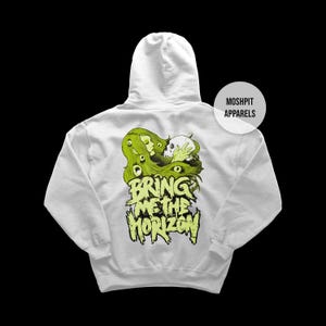 May include: A white hoodie featuring a graphic design on the back. The design includes a green-haired figure, a skull, and the text "BRING ME THE HORIZON" in a distressed, neon green font. The hoodie has a hood and a kangaroo pocket.
