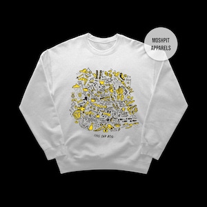 May include: White sweatshirt with a yellow and black doodle design. The design includes various shapes and text, with the words "THIS OLD DOG" at the bottom. The brand name "MOSHPIT APPARELS" is in a white circle on the upper right.