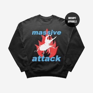 Könnte beinhalten: Schwarzes Sweatshirt mit einem grafischen Design, das einen weißen Käfer in einer roten Flamme zeigt, mit den Wörtern "massive" und "attack" in Blau. Das Sweatshirt hat einen Rundhalsausschnitt und lange Ärmel.