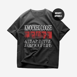 Puede incluir: Camiseta gris oscuro con el texto "KNOCKED LOOSE" sobre una serie de imágenes enmarcadas en rojo. Debajo, el texto "A TEAR IN THE FABRIC OF LIFE". Un círculo negro con "MOSHPIT APPARELS" está en la esquina superior derecha.