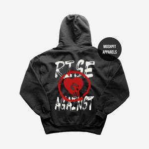 May include: A black hoodie with the words "RISE AGAINST" in white, with a red heart and skull graphic. The hoodie has a hood and a round black tag that says "MOSHPIT APPARELS".