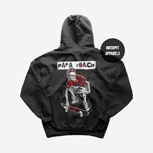 Puede incluir: Sudadera con capucha gris oscuro con un diseño de esqueleto en monopatín y el texto "PAPA ROACH". La sudadera también tiene el texto "MOSHPIT APPARELS" en la parte superior derecha. El diseño es en rojo y blanco.