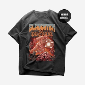 May include: Dark gray t-shirt featuring a graphic design with the text "Slaughter to Prevail" in orange and blue. The design includes a detailed illustration of a demonic figure with a glowing orb and other creatures. The shirt is from Moshpit Apparels.