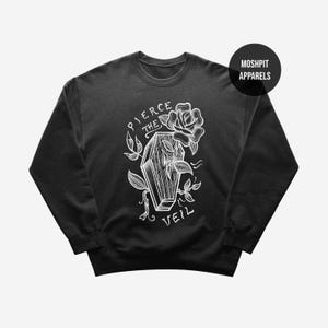 Puede incluir: Sudadera negra con un gráfico blanco. El gráfico presenta un ataúd, una rosa y hojas con las palabras "PIERCE THE VEIL". Un círculo negro con las palabras "MOSHPIT APPARELS" está en la esquina superior derecha.
