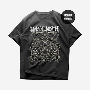 May include: Dark gray t-shirt featuring a detailed graphic design with a skull and figures, and the band name "NAPALM DEATH" in white. The shirt also has a round logo that says "MOSHPIT APPARELS".