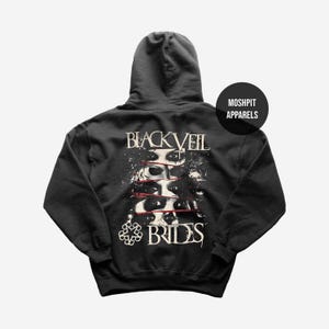 May include: Dark gray hoodie featuring the text "BLACK VEIL BRIDES" above a graphic of eyes with red slashes. The hoodie also has the text "BRIDES" and a logo at the bottom. The brand name "MOSHPIT APPARELS" is on a circular label.