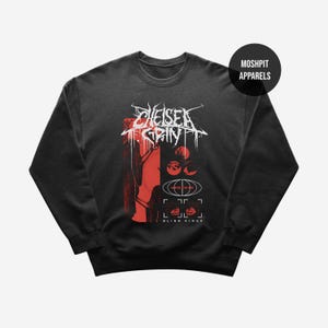 Puede incluir: Sudadera negra de cuello redondo con un diseño gráfico. El diseño presenta el nombre de la banda "Chelsea Grin" en blanco, junto con elementos gráficos rojos y blancos. La sudadera tiene cuello redondo y mangas largas. La marca "Moshpit Apparels" está impresa en un círculo negro.