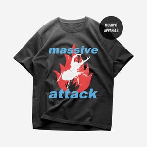 Könnte beinhalten: Schwarzes T-Shirt mit einem weißen Käfer-Design auf einer roten Flammen-Grafik. Die Wörter "massive" und "attack" sind in Blau gedruckt. Das T-Shirt hat einen Rundhalsausschnitt und kurze Ärmel. Der Markenname "MOSHPIT APPARELS" ist auf einem schwarzen Kreis aufgedruckt.