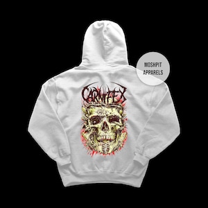 May include: A white hoodie with a detailed skull graphic and the word "CARNIFEX" above it. The skull is yellow and green with red accents. The brand name "MOSHPIT APPARELS" is also visible.