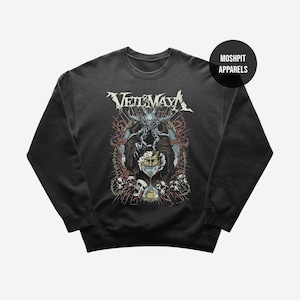 Op de afbeelding: Donkergrijze sweatshirt met een gedetailleerde afbeelding. De afbeelding bevat de bandnaam "Veil of Maya" in wit, een centrale figuur met een masker, en schedels en ingewikkelde ontwerpen in rood, blauw en beige. Het merklogo "Moshpit Apparels" staat in een zwarte cirkel.