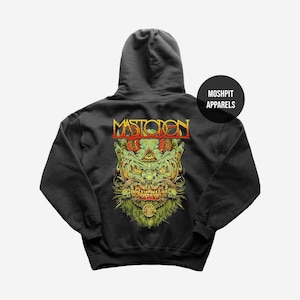 May include: Dark gray hoodie featuring a detailed, colorful graphic of a monster face with the word "MASTODON" above it. The design includes green, yellow, and red accents. A black circle with "MOSHPIT APPARELS" is on the upper right.