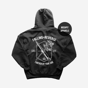May include: Dark grey hoodie with a white graphic on the back. The graphic includes a knife, rose, and text: "FALLING IN REVERSE," "LOVE," "HATE," "FOREVER BY YOUR SIDE," and "EST. 1999." A circular logo on the upper right says "MOSHPIT APPARELS."