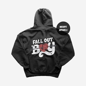 Peut inclure: Sweat à capuche noir avec l'inscription blanche "FALL OUT BOY", orné d'un cœur rouge percé d'une flèche. Le sweat-shirt a une capuche à cordon et une poche kangourou. La marque "MOSHPIT APPARELS" est imprimée sur un cercle noir.
