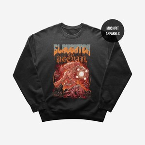 May include: Dark gray sweatshirt featuring a graphic design with the text "SLAUGHTER TO PREVAIL" in orange and blue. The graphic depicts a monster and a figure with a weapon. The brand name "MOSHPIT APPARELS" is in a black circle.